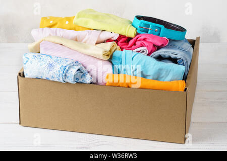 Verschiedene bunte Kleidung in einer Box für den Versand oder Spenden. Kleidung für Kinder und Jugendliche. Stockfoto