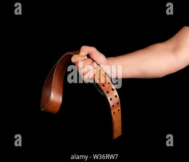 Braun Leder Gürtel mit einer Schnalle in die Hand eines Mannes, schwarzer Hintergrund Stockfoto