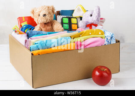 Bunte legere Kleidung, Schreibwaren und Spielwaren in einem Karton für den Versand oder Spenden. Zurück zum Konzept der Schule. Stockfoto
