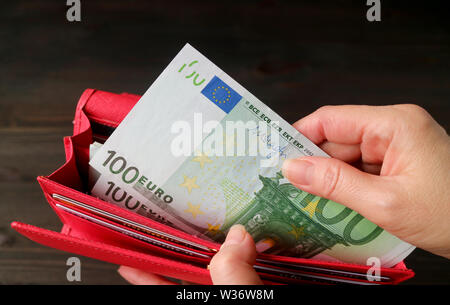 Woman's Hand mit Euro Banknoten aus der roten Tasche Stockfoto