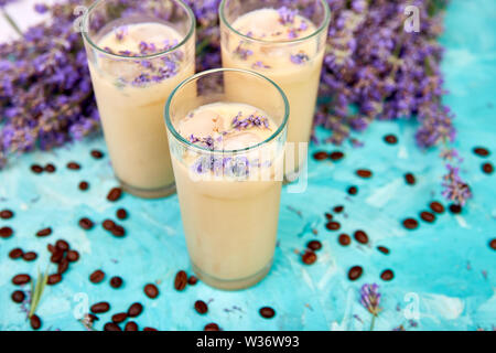 Sommer trinken Eiskaffee mit Lavendel in Glas und Kaffeebohnen auf blauem Hintergrund. Guten Morgen Konzept. Baeutiful Eis Kaffee. Stockfoto