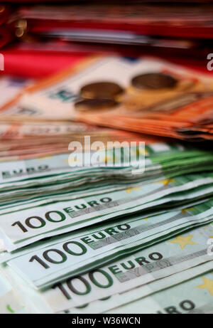 Vertikale Bild von closeup Verbreitung der Euro-Banknoten mit verschwommenen Münzen und eine Brieftasche im Hintergrund Stockfoto