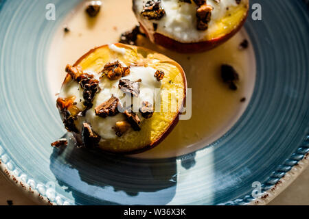 Gebackene Pfirsiche mit griechischem Joghurt, gerösteten Nüssen und Honig/Nektarinen. Organische Dessert. Stockfoto