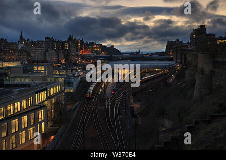 Ein Abellio scotrail Klasse 380 am Bahnhof Edinburgh Waverley Station ankommen, East End bei Sonnenuntergang mit der Edinburgh skyline Stockfoto