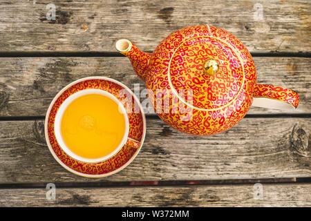 Gemusterte Rot & Orange Teekanne, Tasse & Untertasse Stockfoto