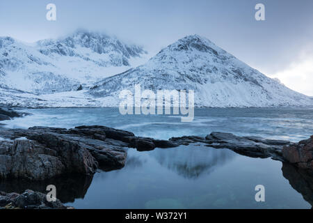 Winterblick auf Senja Insel. Wolkige Dämmerung oder Nacht in Bergen und Fjorden, Winterlandschaft, Fischerdorf, Norwegen schöne weihnachtszeit, Tromso Stockfoto