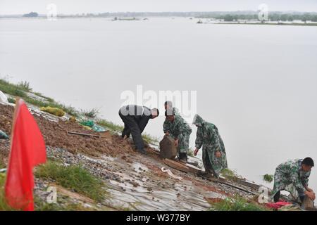 Yugan, der chinesischen Provinz Jiangxi. 13. Juli, 2019. Menschen arbeiten ein Deich in Jiangbu Township von Yugan County, im Osten der chinesischen Provinz Jiangxi, am 13. Juli 2019 zu verstärken. Der Wasserstand der Poyang See ist obige Warnung Linie durch kontinuierliche starke Regenfälle. Credit: Hu Chenhuan/Xinhua/Alamy leben Nachrichten Stockfoto