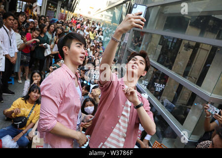 Bangkok, Thailand. 13. Juli 2019. Thailändische Schauspieler Saint Suppapong Udomkaewkanjana und Perth Tanapon selfies Sukhumpantanasen nehmen mit den Fans auf ein Fan treffen in Siam Viertel von Bangkok. Die beiden beliebten Schauspieler vor kurzem zusammen in der thailändischen TV-Drama "Erinnerungen" die Hauptrolle. Saint ist die Aufnahme der Fotos. Stockfoto