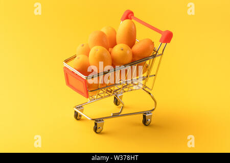 Kumquat kumquat oder in einem Warenkorb auf gelbem Hintergrund, Obst shopping Konzept Stockfoto