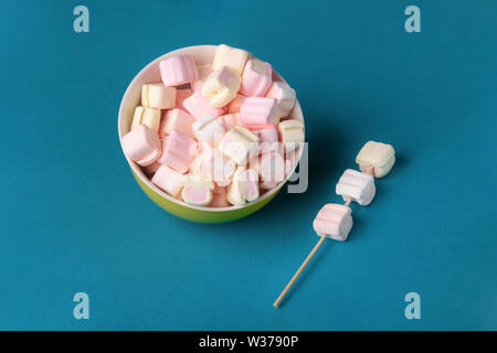 Bunte Marshmallows in der Platte auf blauem Hintergrund Stockfoto