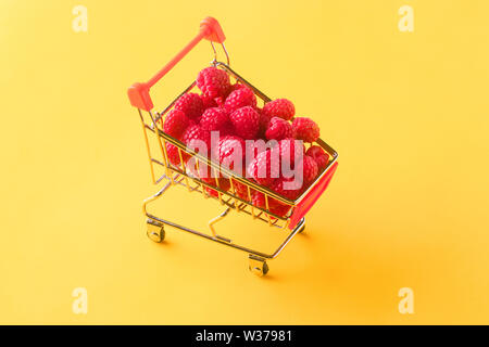 Reife Himbeeren im Warenkorb auf orange Hintergrund, Konzept kaufen süßen Beeren Stockfoto