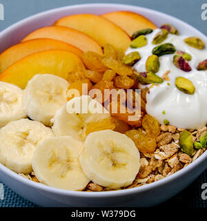 Gesunde vegetarische Frühstück Schüssel Müsli Früchte und Nüsse mit Joghurt und Golden Sultaninen Stockfoto