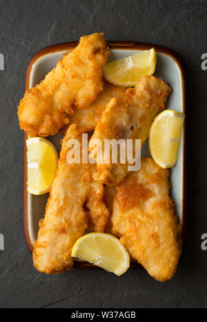 Filets von Frittierten schmollen, Trisopterus luscus, die im Teig beschichtet wurden und tief zu Hause gebratenen Fisch und Chips Abendessen zu machen. Die SCHMOLLEND Stockfoto