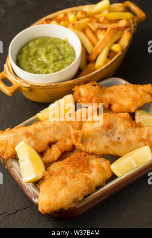 Filets von Frittierten schmollen, Trisopterus luscus, die im Teig beschichtet wurden und tief zu Hause gebratenen Fisch und Chips Abendessen zu machen. Die SCHMOLLEND Stockfoto