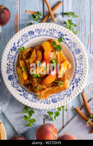 Köstliche Dessert mit frischen Pfirsichen, gebraten mit Ahornsirup und French Toast Stockfoto