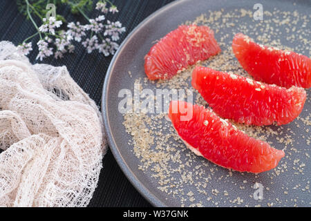 Scheiben frischer Grapefruit mit braunem Zucker auf einer Platte Stockfoto