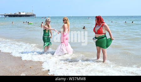 Brighton UK 13. Juli 2019 - Diese Damen ein Paddel nach der Teilnahme im März der Meerjungfrauen Parade als Brighton Beach genießen Sie besetzt ist, wie die Besucher der heißen Sonne mit Temperaturen wieder Erreichen der Mitte der 20er Jahre in den Süden Osten genießen. Foto: Simon Dack/Alamy leben Nachrichten Stockfoto