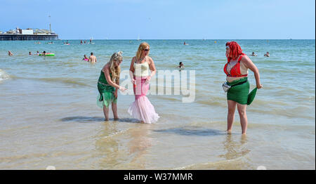 Brighton UK 13. Juli 2019 - Diese Damen ein Paddel nach der Teilnahme im März der Meerjungfrauen Parade als Brighton Beach genießen Sie besetzt ist, wie die Besucher der heißen Sonne mit Temperaturen wieder Erreichen der Mitte der 20er Jahre in den Süden Osten genießen. Foto: Simon Dack/Alamy leben Nachrichten Stockfoto