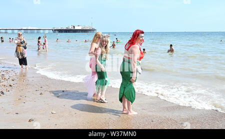 Brighton UK 13. Juli 2019 - Diese Damen ein Paddel nach der Teilnahme im März der Meerjungfrauen Parade als Brighton Beach genießen Sie besetzt ist, wie die Besucher der heißen Sonne mit Temperaturen wieder Erreichen der Mitte der 20er Jahre in den Süden Osten genießen. Foto: Simon Dack/Alamy leben Nachrichten Stockfoto
