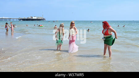 Brighton UK 13. Juli 2019 - Diese Damen ein Paddel nach der Teilnahme im März der Meerjungfrauen Parade als Brighton Beach genießen Sie besetzt ist, wie die Besucher der heißen Sonne mit Temperaturen wieder Erreichen der Mitte der 20er Jahre in den Süden Osten genießen. Foto: Simon Dack/Alamy leben Nachrichten Stockfoto
