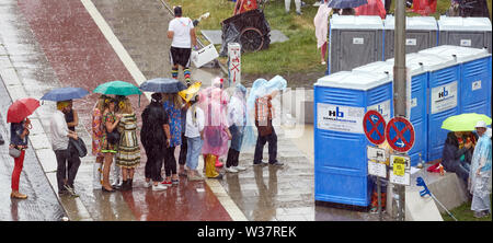 Hamburg, Deutschland. 13. Juli, 2019. Besucher des Schlagermoves stand mit Sonnenschirmen vor der mobile Toiletten auf Hellgoländer Allee. Quelle: Georg Wendt/dpa/Alamy leben Nachrichten Stockfoto
