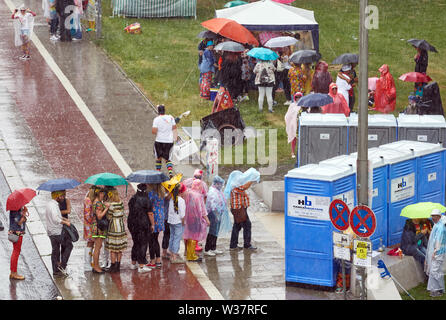 Hamburg, Deutschland. 13. Juli, 2019. Besucher des Schlagermoves stand mit Sonnenschirmen vor der mobile Toiletten auf Hellgoländer Allee. Quelle: Georg Wendt/dpa/Alamy leben Nachrichten Stockfoto