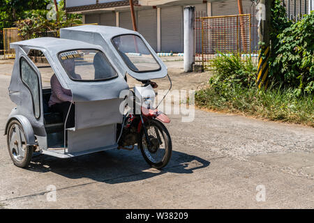 Puerto Princesa, Palawan, Philippinen - 3. März 2019: Blick auf die Straße. Einfachen grauen taxi Motor - Dreirad unterwegs. Stockfoto