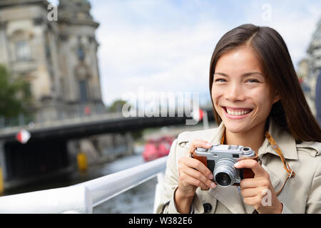 Touristische Frau auf Boot Tour Berlin, Deutschland Spaß lächelte glücklich und genießen Sie Tag Kreuzfahrt Fotos mit Kamera. Europa reisen urlaub ferien Konzept. Multirassischen asiatischen kaukasische Frau. Stockfoto