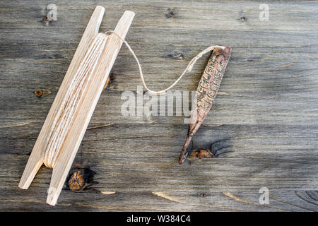 Alte Griff für vertikale blinken Raubfische. Kupfer geschmiedet Spinner und Haspel mit Seil auf Holz- rustikalen Hintergrund. Stockfoto