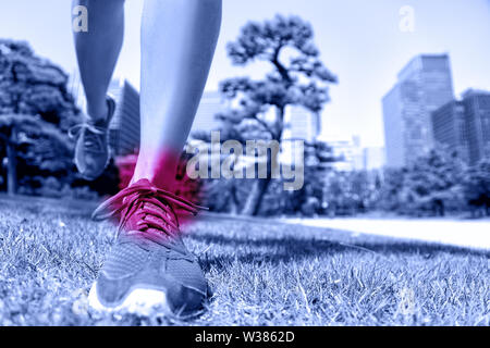Sportverletzung - Läufer die Füße und Knöchel Schmerzen. Nahaufnahme von Laufschuhen Landung auf weichem Gras mit roter Kreis angezeigt verletzen, Bänder und Gelenke durch ein Trauma verursacht. Stockfoto