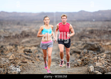 Aktiver sport Menschen Läufer auf Rocky Trail Running Pfad im freien Training für Marathon oder Triathlon. Fit fitness Modell Mann und die asiatische Frau Ausbildung zusammen draußen auf Big Island, Hawaii, USA. Stockfoto