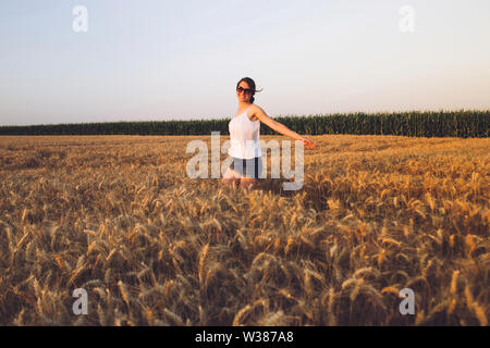 Glückliche junge Frau im Sommerweizenfeld Stockfoto