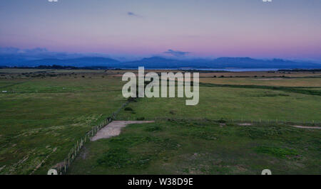 Luftaufnahme über Küstenlandschaft mit Gebirge im Hintergrund bei Dämmerung in Anglesey, North Wales, UK Stockfoto