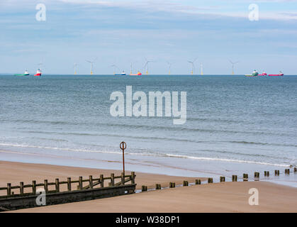 Offshore-versorgungsschiffen durch Windenergieanlagen im Offshore Windpark verankert, Aberdeen Strand mit groyne, Schottland, Großbritannien Stockfoto