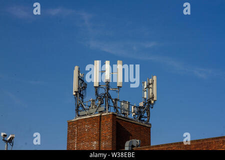 WIfi oder Handy Antenne gesehen auf der Spitze eines re Backsteinbau vor blauem Himmel Stockfoto