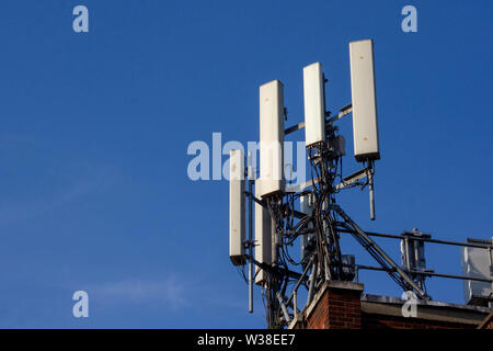 WIfi oder Handy Antenne gesehen auf der Spitze eines re Backsteinbau vor blauem Himmel Stockfoto