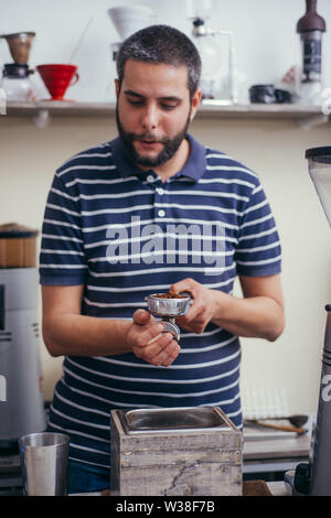 Männliche barista über eine Kaffeemaschine eine schöne Tasse Kaffee zu machen. Cafe Arbeiter Vorbereitung einen Kaffee Stockfoto