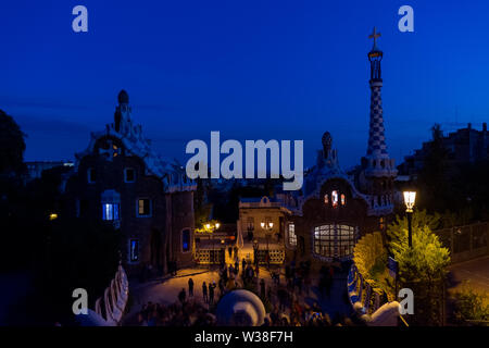 Auf Barcelona vom Park Güell auf den Sonnenuntergang. Im Vordergrund die bunten Gebäude vom Haupteingang. Barcelona, Spanien. Stockfoto