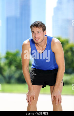 Müde Mann runner erschöpft nach dem Sport ausüben. Männliche jogger Fang Atem schwitzen nach dem Lauf Training im Sommer mit städtischen Hintergrund im Central Park, New York City, Manhattan, USA, USA Stockfoto