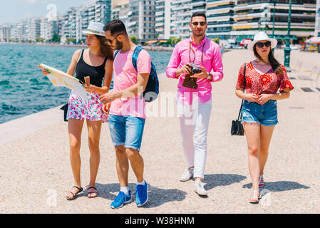 Ein paar ist das Lesen einer Karte, während die anderen Fotos ist, die ihren Sommer Urlaub. Stockfoto