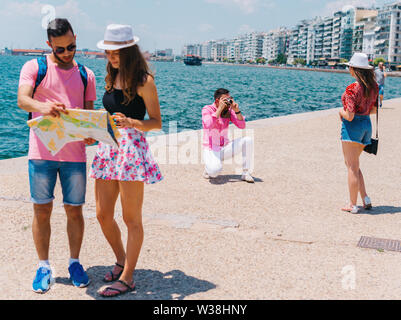 Ein paar ist das Lesen einer Karte, während die anderen Fotos ist, die ihren Sommer Urlaub. Stockfoto