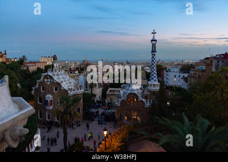 Auf Barcelona vom Park Güell auf den Sonnenuntergang. Im Vordergrund die bunten Gebäude vom Haupteingang. Barcelona, Spanien. Stockfoto