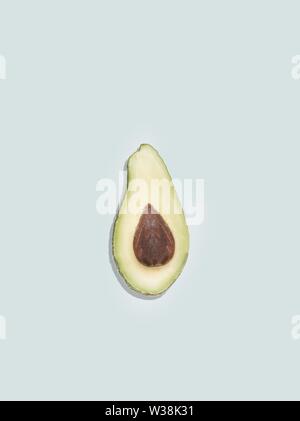 Natürliche schöne Tapete mit einer isolierten geschnitten Avocado auf einem Hellblauer Hintergrund Stockfoto