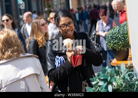 Frau mit frisch gekauftem Eis im Zentrum von York, North Yorkshire, England, Großbritannien. Stockfoto