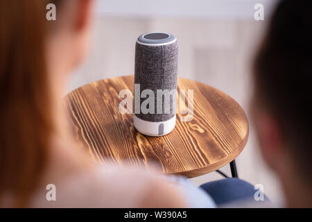 Ansicht der Rückseite des Paar sitzt auf einem Sofa in der Nähe von drahtlosen Lautsprecher Stockfoto