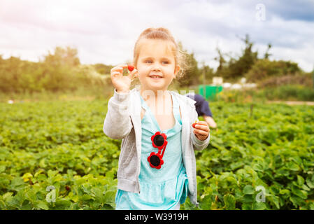 Süße Mädchen Kommissionierung Erdbeeren im Garten Stockfoto