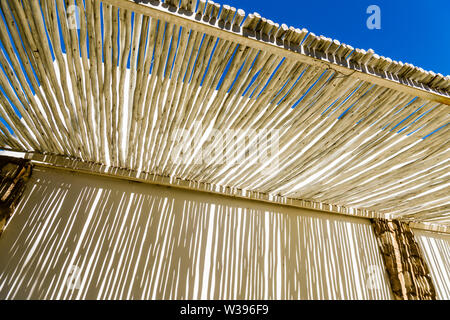 Abstrakte Schatten auf einer weißen Wand durch den Overhead Vordach von rustikal Holz, in einem Hotel in Namibia Stockfoto