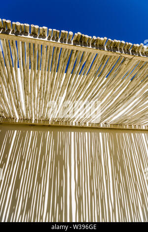 Abstrakte Schatten auf einer weißen Wand durch den Overhead Vordach von rustikal Holz, in einem Hotel in Namibia Stockfoto