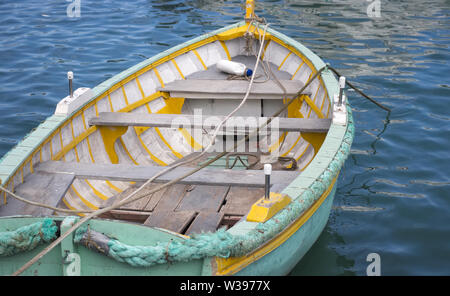 Eine alte weiß und türkis hölzernen Ruderboot ist am Liegeplatz in das Mittelmeer leer. typischen kleinen Boot an der Küste von Malta. Stockfoto