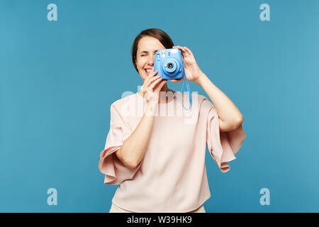 Junge Fotografin mit blauen Kamera vor, die Sie während der Aufnahme Stockfoto
